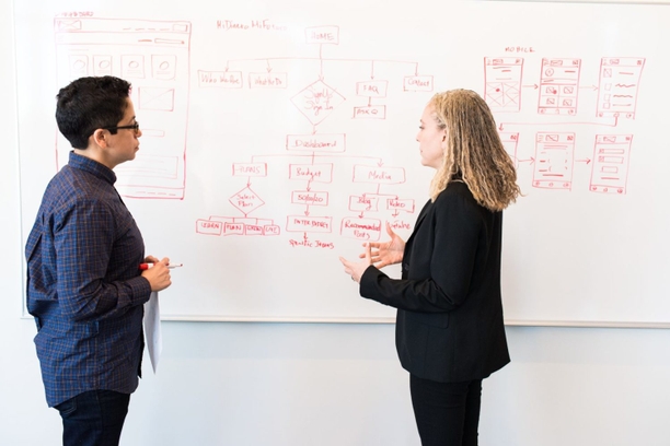 two people brainstorming at a white board